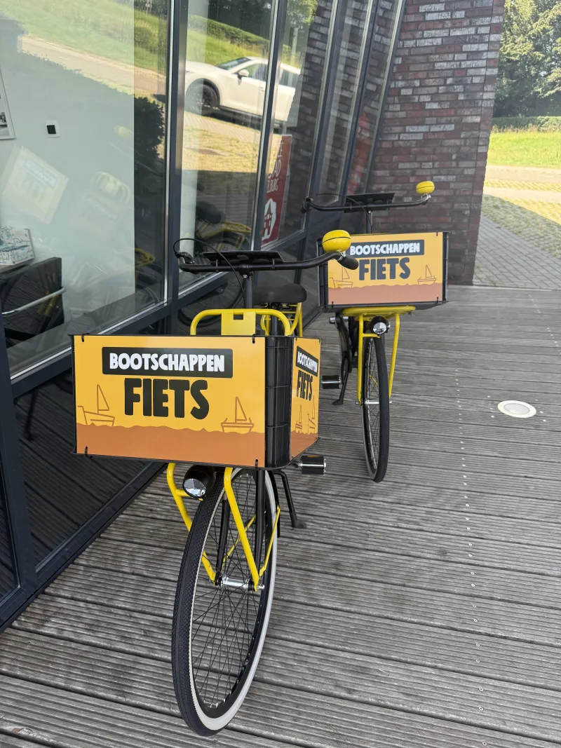 Gele bootschappenfietsen bij het havenkantoor in de haven van Elburg